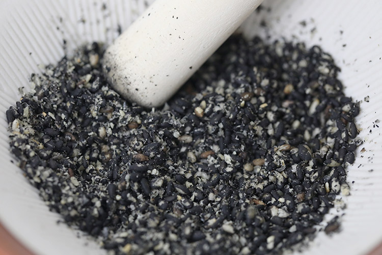 Crush the black sesame seeds in a grinding bowl.